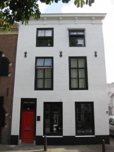 a white building with a red door at Bed and Breakfast de Kleyne Wereld in Vlissingen