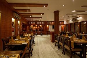 un restaurante con mesas de madera y sillas en una habitación en Sinclairs Siliguri en Siliguri
