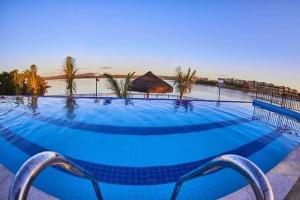 a large blue swimming pool with a view of the beach at Ilhas do Lago Eco Resort in Caldas Novas