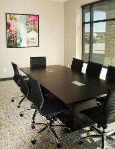 Hyatt Place Altoona/Des Moines في ألتونا: قاعة اجتماعات مع طاولة سوداء كبيرة وكراسي