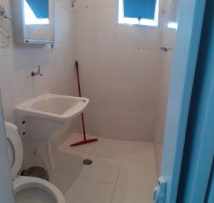 uma casa de banho branca com um lavatório e um WC em Residencial Alemão no Guarujá