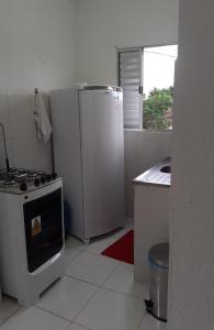 uma cozinha branca com um fogão e um frigorífico em Residencial Alemão no Guarujá
