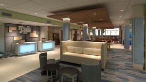 Holiday Inn Express & Suites Woodside LaGuardia Airport في كوينز: لوبي فيه شاشتين وطاولات وكراسي