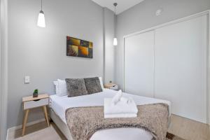 オークランドにあるStunning Auckland Central Apartmentの白いベッドルーム(ベッド1台、テーブル付)