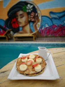 einen Pfannkuchen mit Bananen und Erdbeeren auf einem Teller in der Unterkunft Surfari Punta Rocas in Punta Negra