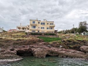 a house on a hill next to a body of water at Ithaca in Perdika