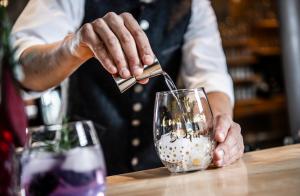 un homme verse une boisson dans un verre dans l'établissement Viel Nois Guest House, à Funes