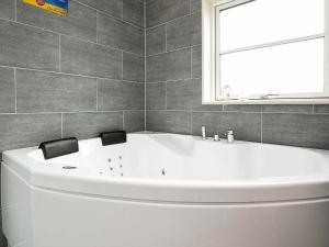 a white bath tub in a bathroom with a window at 14 person holiday home in V ggerl se in Marielyst