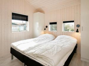 a large bed in a room with two windows at 14 person holiday home in V ggerl se in Marielyst