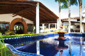a swimming pool with a fountain in front of a building at Hotel El Rebozo in Valle de Bravo