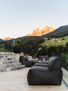 two black couches sitting on a deck with a fireplace at Viel Nois Guest House in Funes