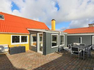 een klein huis met een oranje dak en een patio bij 6 person holiday home in Lemvig in Ferring
