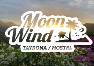a sign for the moron wind hotel in a field of flowers at Moon Wind Tayrona Hostel by Rotamundos in El Zaino