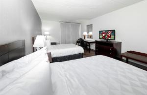 a hotel room with two beds and a desk at Red Roof PLUS Newark Liberty Airport - Carteret in Carteret