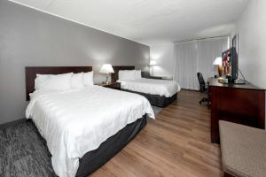a hotel room with two beds and a flat screen tv at Red Roof PLUS Newark Liberty Airport - Carteret in Carteret