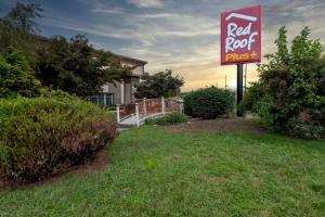 a red roof plus sign in front of a house at Red Roof PLUS Newark Liberty Airport - Carteret in Carteret
