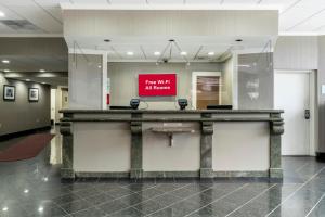 a reception desk in a lobby with a red sign at Red Roof PLUS Newark Liberty Airport - Carteret in Carteret