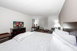 a bedroom with a white bed and a living room at Red Roof PLUS Newark Liberty Airport - Carteret in Carteret