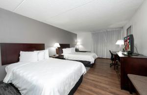 a hotel room with two beds and a desk at Red Roof PLUS Newark Liberty Airport - Carteret in Carteret