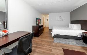 a hotel room with a bed and a desk and a desk at Red Roof PLUS Newark Liberty Airport - Carteret in Carteret