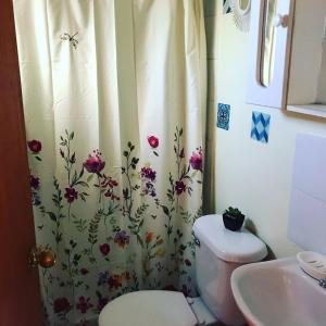uma casa de banho com um WC e uma cortina de chuveiro com flores em Cabañas Santa Teresita em Algarrobo