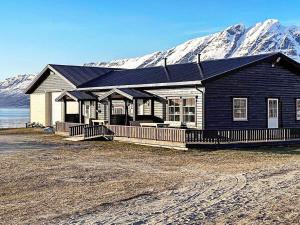 Holiday home Hamnvik في Hamnvik: منزل أسود مع جبال مغطاة بالثلج في الخلفية