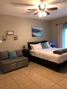a bedroom with a bed and a couch and a ceiling fan at The Comfi Coral - Large 1 Bedroom Studio A in Baytown