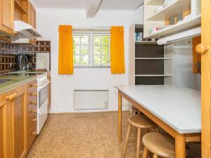 a kitchen with a table and some orange curtains at 6 person holiday home in R m in Rømø Kirkeby