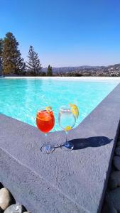 two glasses sitting on a ledge next to a swimming pool at Domus Lake Resorts in Villa Carlos Paz