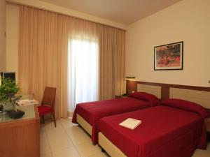 una camera d'albergo con letto rosso e scrivania di La Costiera Hotel a Marina di Varcaturo