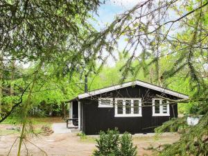 a black house in the middle of a forest at 6 person holiday home in Str by in Strøby
