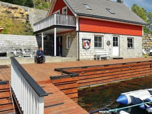 a man sitting on a wooden deck next to a house at 4 person holiday home in Urangsv g in Ervik