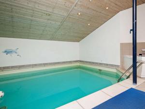 a large swimming pool with blue water in a room at 12 person holiday home in V ggerl se in Marielyst