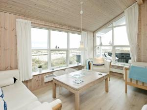 a living room with a table and chairs and windows at 6 person holiday home in S by in Sæby