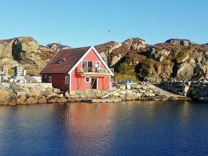a red house on the shore of a body of water at 9 person holiday home in Utsira-By Traum in Utsira