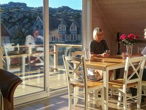 una mujer sentada en una mesa en un balcón en Four-Bedroom Holiday home in Utsira, en Utsira