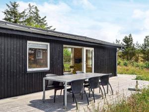 uma casa preta com uma mesa e cadeiras num deque em 6 person holiday home in Fan em Sønderho