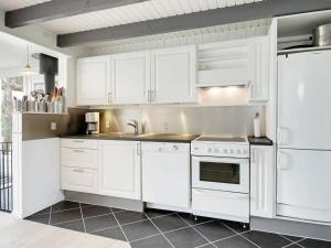 una cocina con armarios blancos y electrodomésticos blancos en 6 person holiday home in Hemmet, en Falen