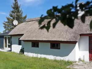 a white house with a thatch roof with a yard at 6 person holiday home in Vesl s in Øsløs