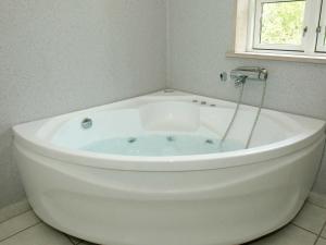 a white bath tub in a bathroom with a window at Lovely Cottage in Aakirkeby with Sauna in Vester Sømarken