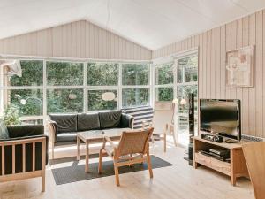 a living room with a couch and a tv at Lovely Cottage in Aakirkeby with Sauna in Vester Sømarken