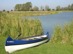 ein blaues und weißes Boot auf dem Gras in der Nähe des Wassers in der Unterkunft 12 person holiday home in Otterndorf in Otterndorf