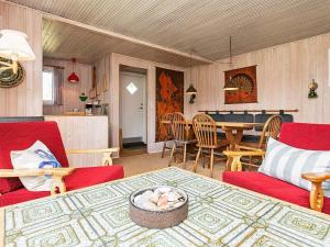 Two-Bedroom Holiday home in Ringkøbing 9 في سوندرفيغ: غرفة معيشة مع كراسي حمراء وطاولة
