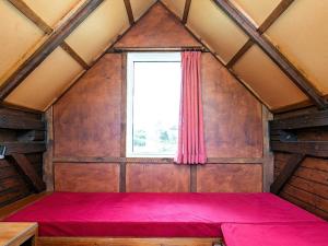 Cama roja en habitación con ventana en Two-Bedroom Holiday home in Ringkøbing 9, en Søndervig