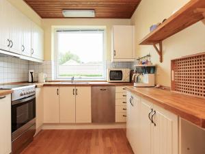 a kitchen with white cabinets and a window at 4 person holiday home in Dannemare in Dannemare