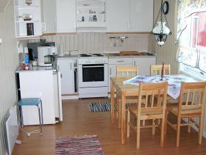 6 person holiday home in Vevelstad في Vevelstad: مطبخ مع طاولة وكراسي وأدوات بيضاء