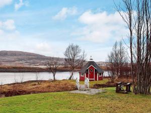 una pequeña casa roja al lado de un lago en 6 person holiday home in Vevelstad, en Vevelstad