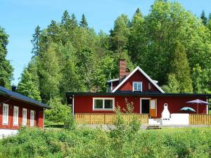 una casa roja con árboles en el fondo en Four-Bedroom Holiday home in Mellerud, en Dals Rostock