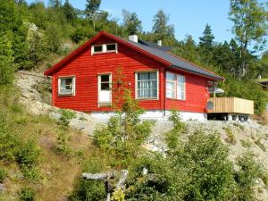 Four-Bedroom Holiday home in Norheimsund في نورهايمسوند: منزل احمر على جانب تل