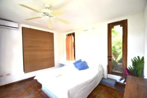 1 dormitorio con cama blanca y ventilador de techo en Villas Punta India en Ostional